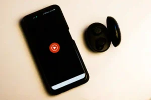 Smartphone with YouTube app and wireless earbuds symbolizing YouTube automation and earning from home